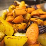 Close-up of roasted winter vegetables including carrots, parsnips, and swede seasoned with herbs and lightly caramelised.