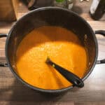 Hidden veg tomato sauce in a black pot, ready to serve, with a smooth, vibrant orange colour.